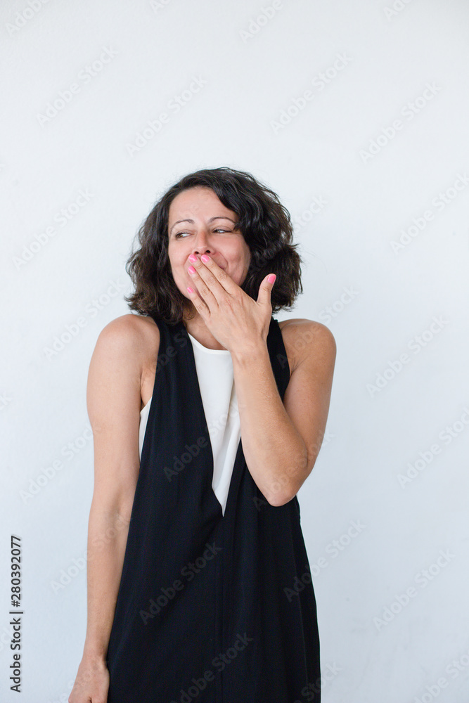 Shy woman closing mouth. Attractive happy woman holding hand on lips and looking away isolated on grey background. Emotion concept Shy woman closing mouth. Attractive happy woman holding hand on lips and looking away isolated on grey background. Emotion concept