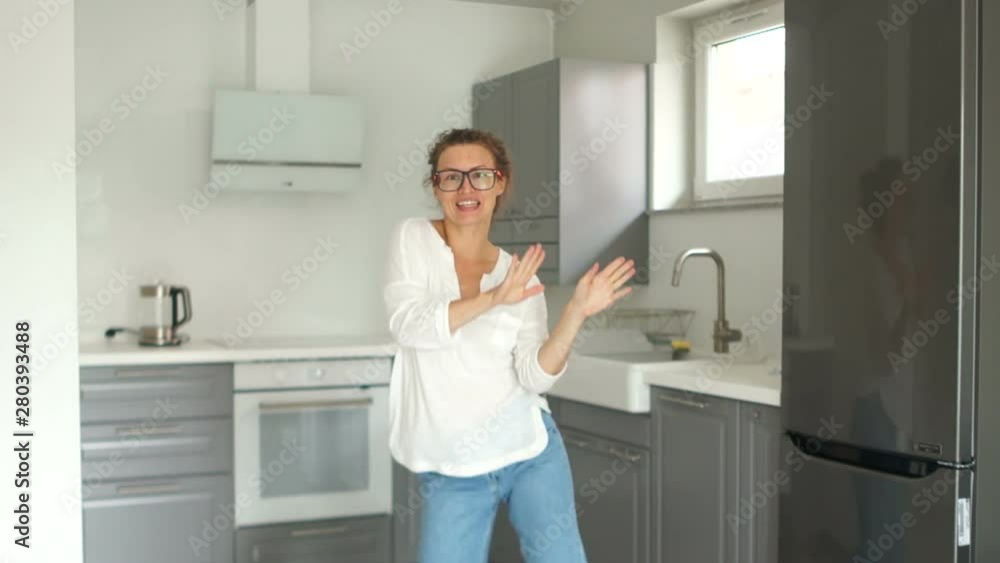 Fanny video portrait of a beautiful young woman dancing in her new kitchen after the repair is completed. Real estate repair concept Fanny video portrait of a beautiful young woman dancing in her new kitchen after the repair is completed. Real estate repair concept