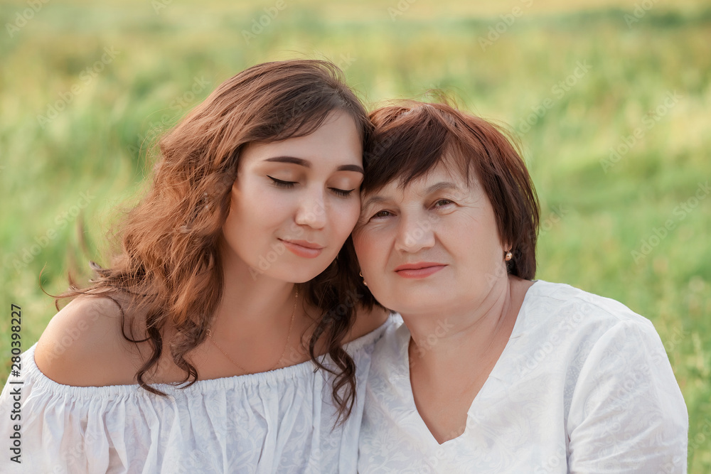 Mom and daughter are sitting on the grass enjoying a walk