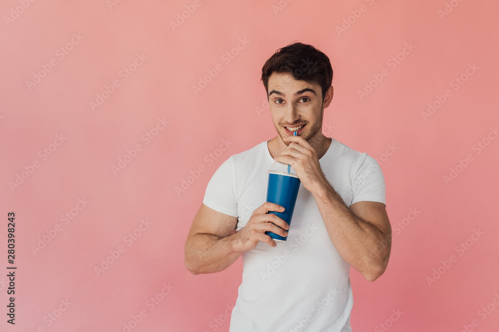 muscular smiling man in white t-shirt drinking beverage isolated on pink muscular smiling man in white t-shirt drinking beverage isolated on pink