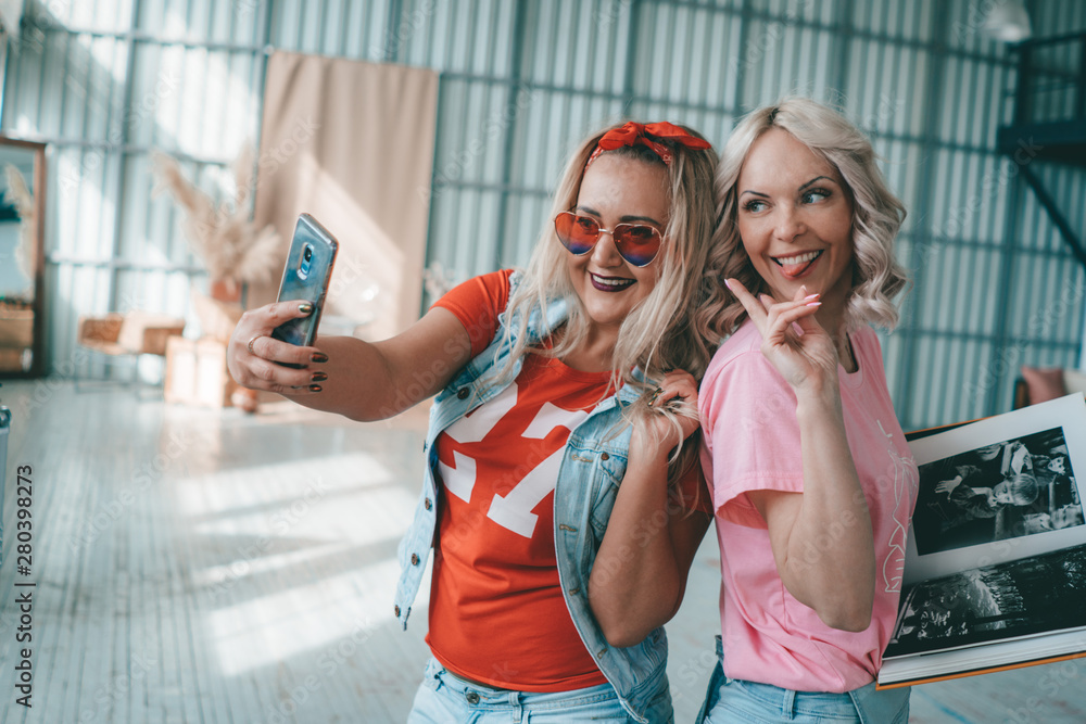 Two beautiful stylish young blondes taking selfies