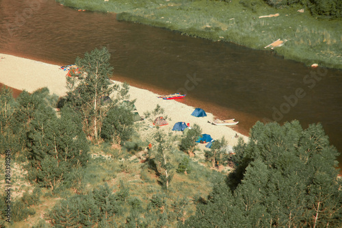 Camping tents on the beach. Tourists rafting on the river on a halt photo