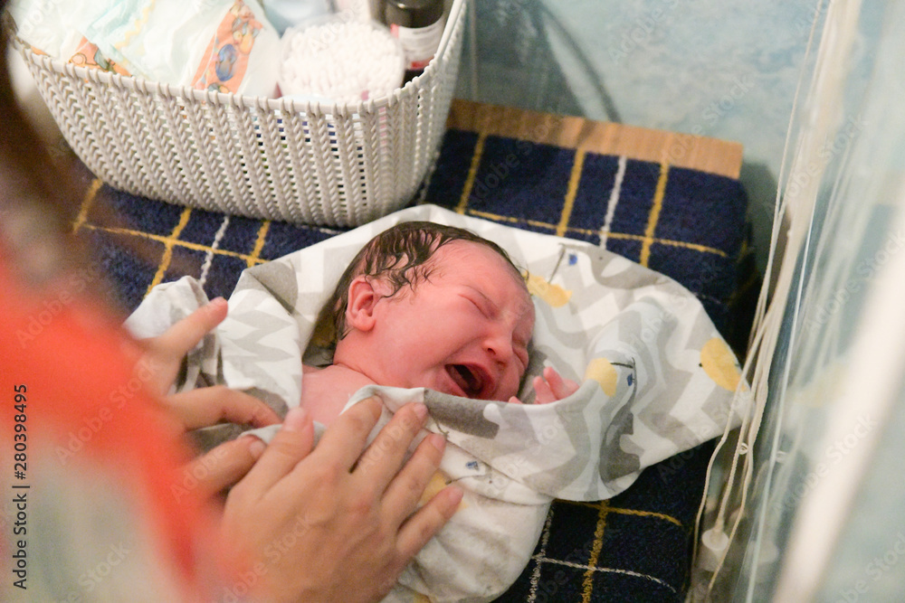 Crying baby when swaddling. A newborn 1 week old baby being examined by