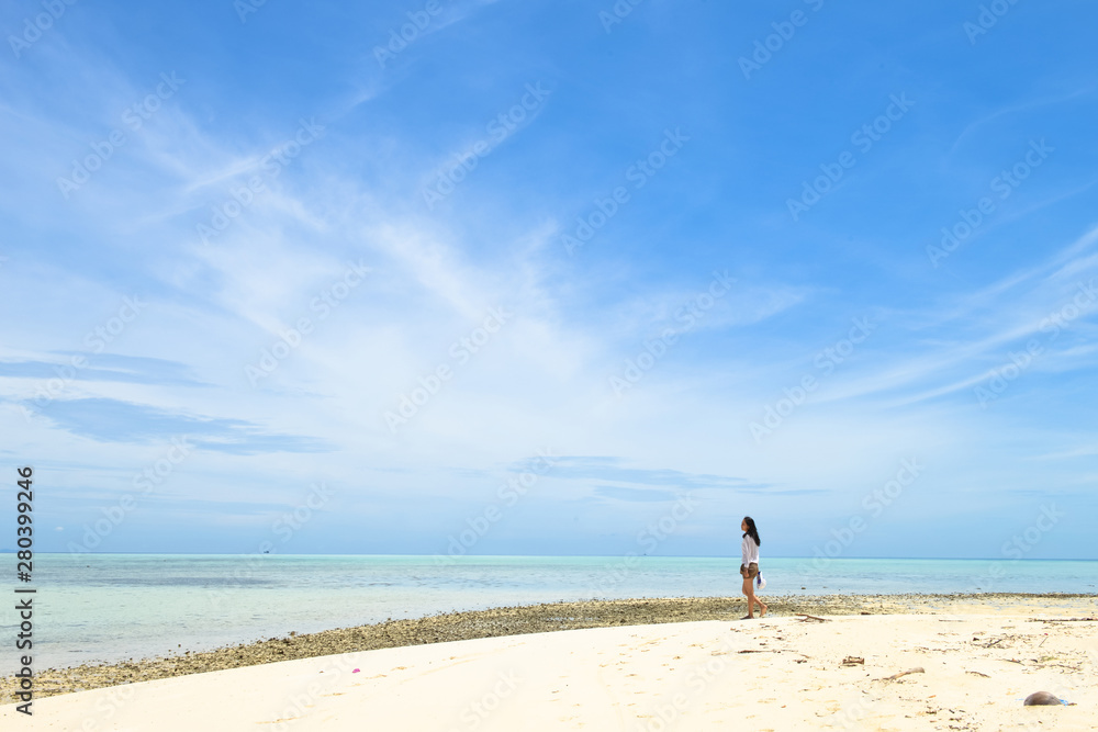 single young Asian girl walking on tropical white sand beach, at Pulau Sibuan, Semporna, Sabah, Malaysia