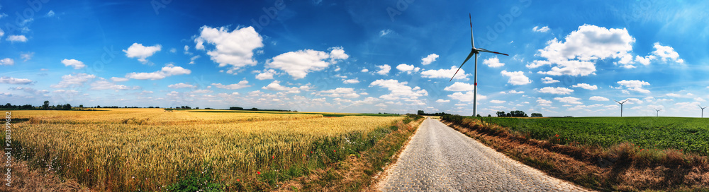 Panoramic summer landscape with country road and wind turbines