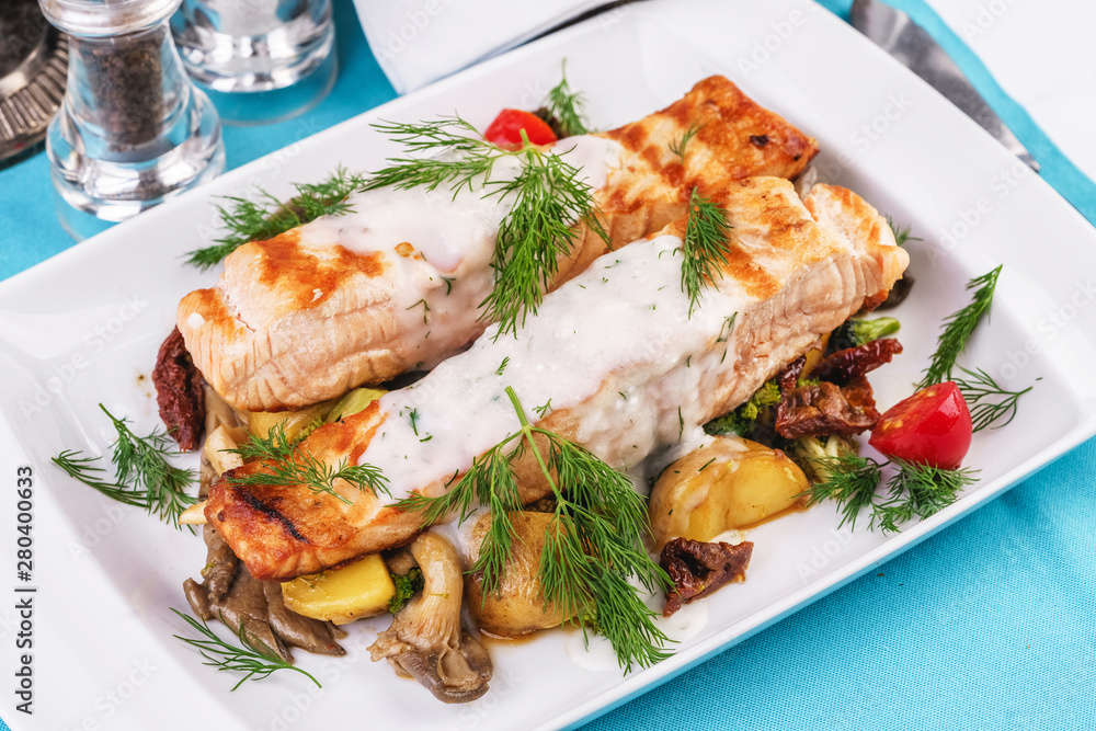 Seafood, Mediterranean cuisine. Grilled salmon fish steak with grilled vegetables and oyster mushrooms. Caucasian kitchen Seafood, Mediterranean cuisine. Grilled salmon fish steak with grilled vegetables and oyster mushrooms. Caucasian kitchen