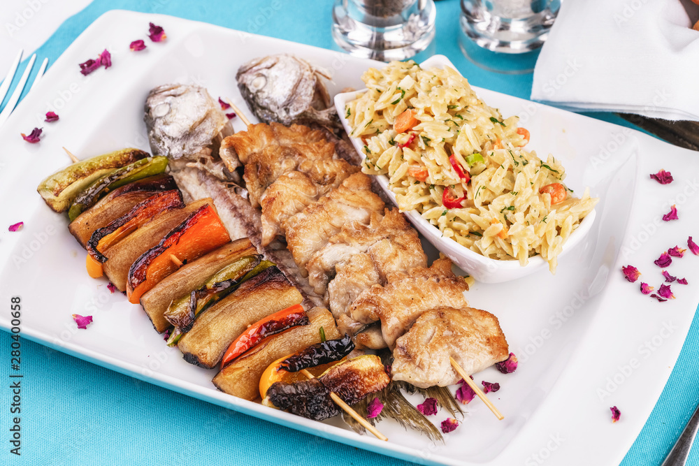 Mediterranean dish, Georgian recipe. Baked chicken skewers with lemon, vegetables, pepper, zucchini, eggplants and grilled tomatoes with spices, and steamed rice