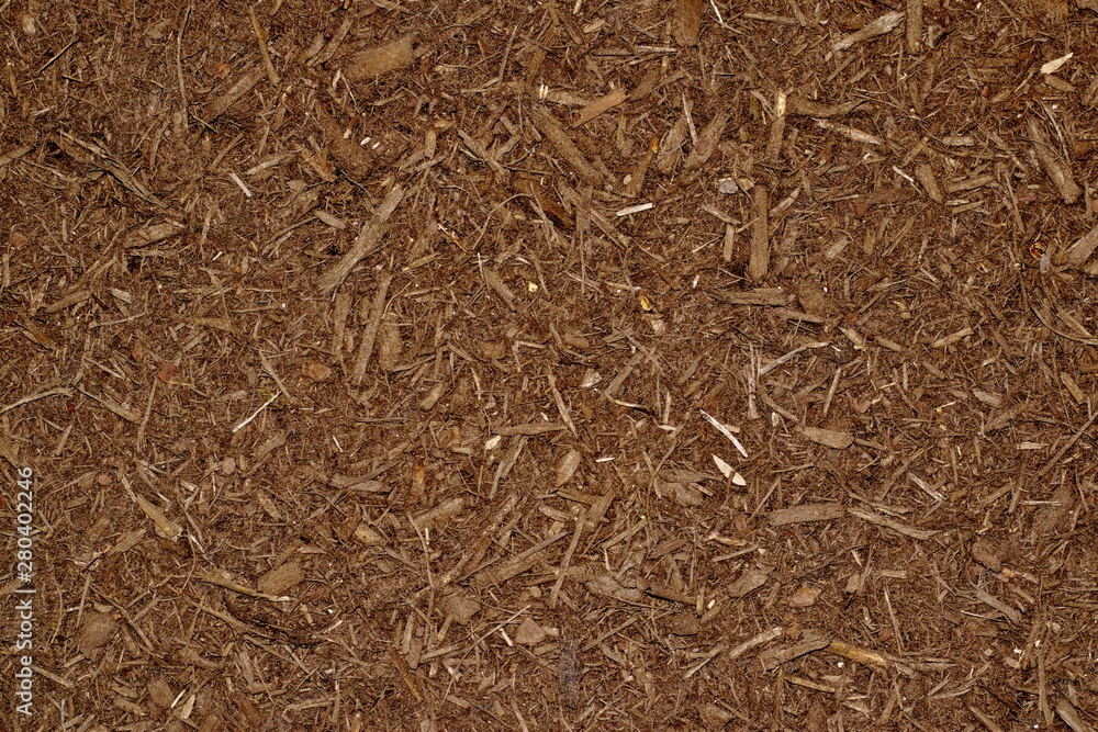 Dark brown wood chip mulch scattered thickly in a landscaped garden area. Dark brown wood chip mulch scattered thickly in a landscaped garden area.