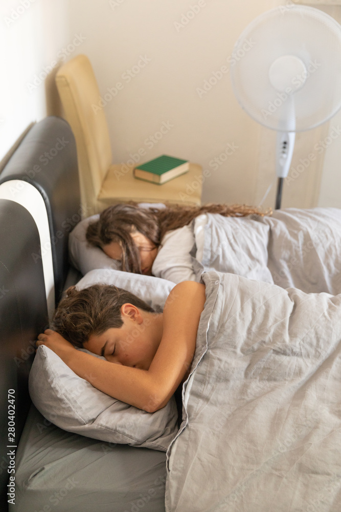A boy and a girl sleep refreshed by a fan A boy and a girl sleep refreshed by a fan
