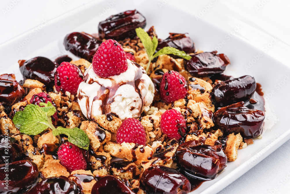 Fototapeta premium Berry-chocolate cake with ice cream, chocolate sauce and dates