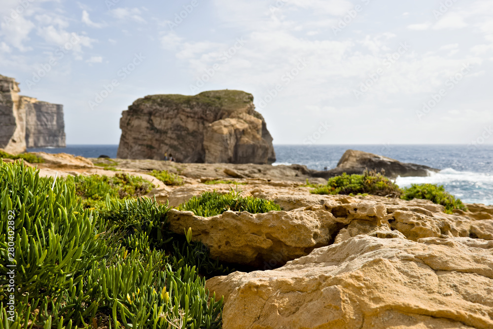 Scenic view of beautiful green vegetation and cliffs, fungus rock and blue ocean at dweira bay in gozo, malta.