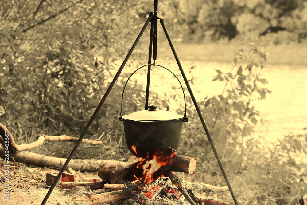 cooking delicious tasty food outdoors on fire in iron pot in summer in good weather with wood from forest cooking delicious tasty food outdoors on fire in iron pot in summer in good weather with wood from forest