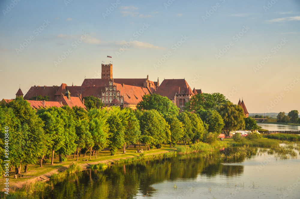 The Castle of the Teutonic Order in Malbork, Poland with the Nogat river shore. 13th-century castle is the largest castle in the world measured by land area and a UNESCO World Heritage Site