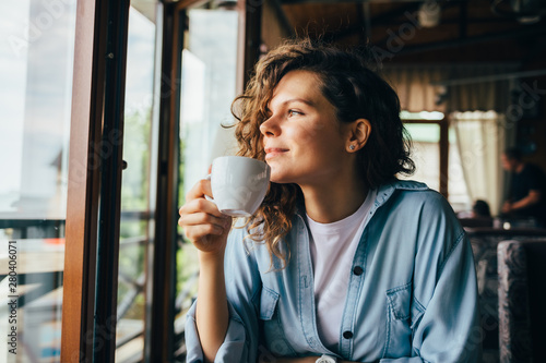 Smiling calm young woman drinking coffee photo
