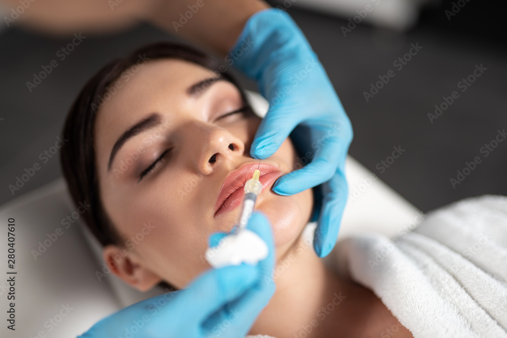 Beautician in sterile gloves making injection in lady lips Beautician in sterile gloves making injection in lady lips