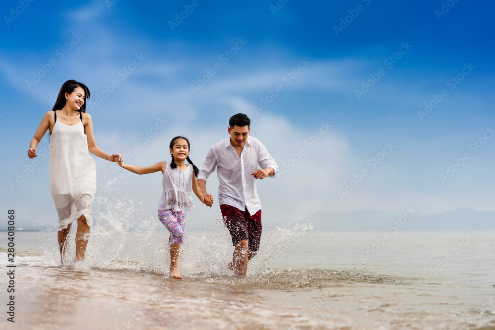 Happy family day: having fun at the beach.Father mothe and girl hold hands and run with fun along edge of sea
