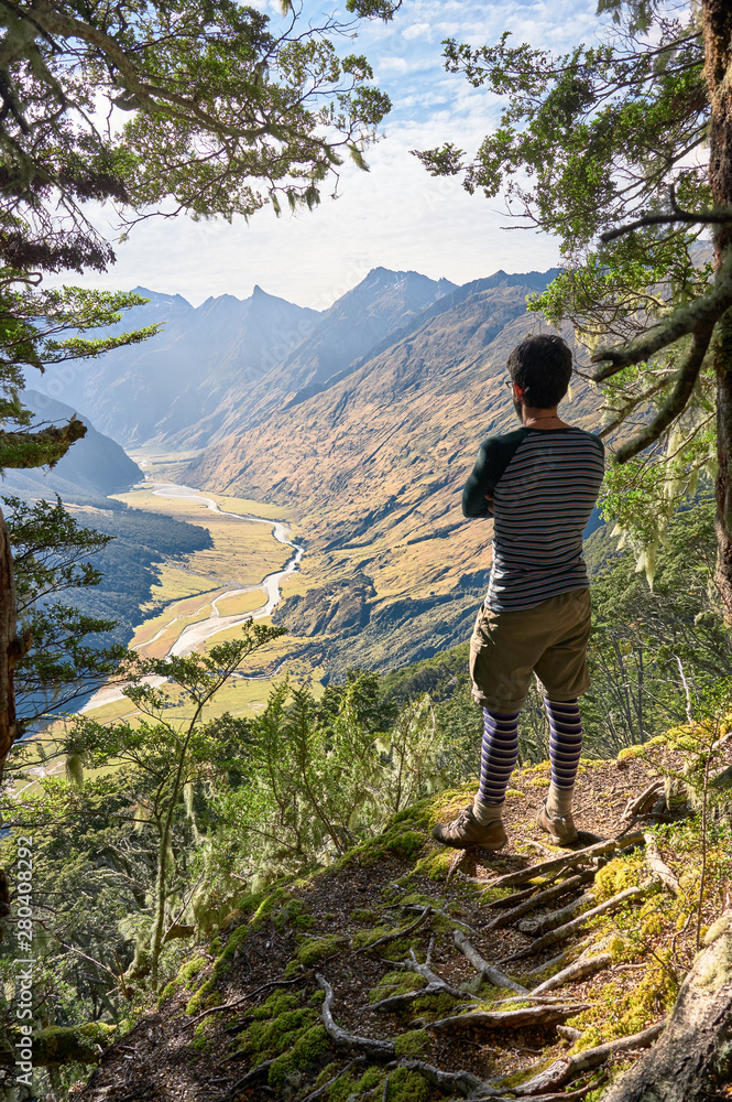 Naklejka premium Hiker wearing trekking clothes looks over beautiful valley in New Zealand