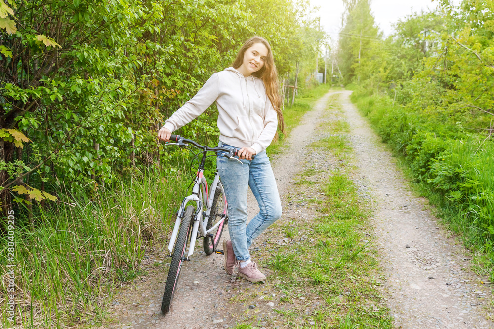 Naklejka premium Young woman riding bicycle in summer city park outdoors. Active people. Hipster girl relax and rider bike. Cycling to work at summer day. Bicycle and ecology lifestyle concept