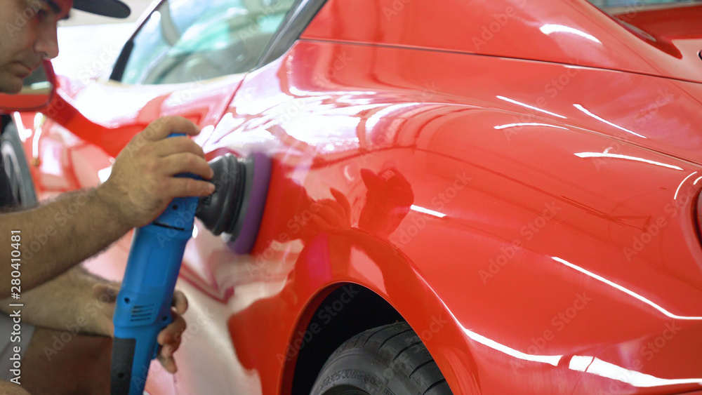 In the car center (in the garage), professionals polish a new sports car. Luxury car polishing. Concept of: Racing, Sport car, New, Slow motion, Nascar, Red, Chrome plated.