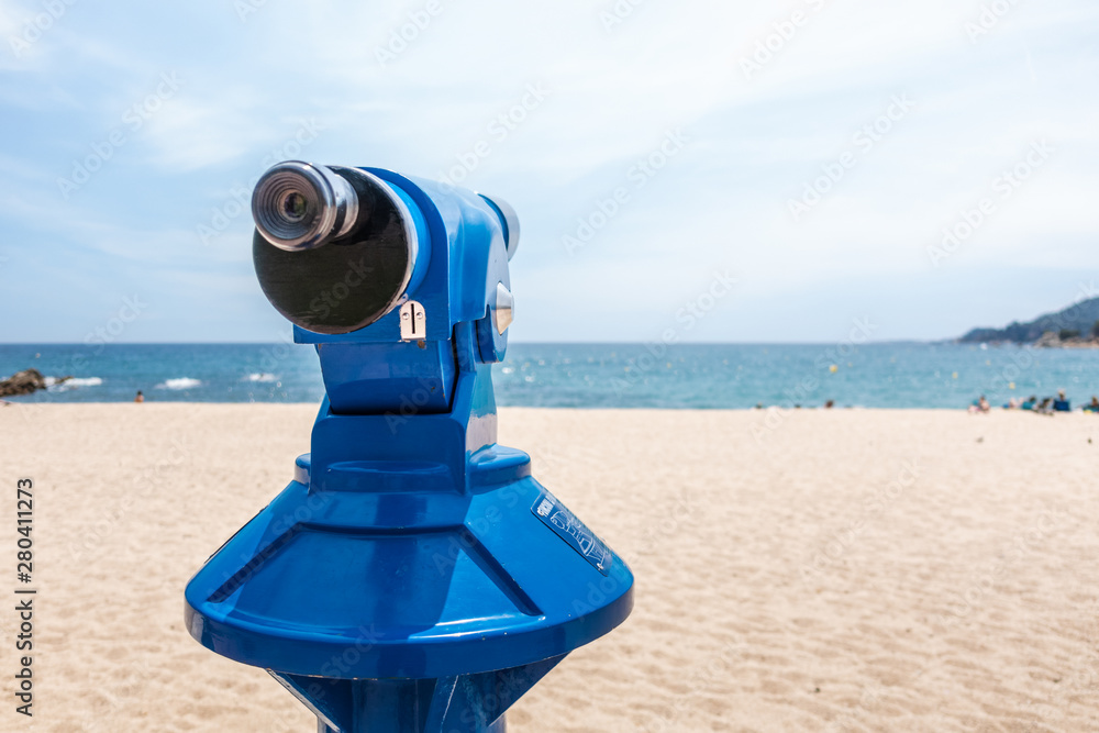 public blue spyglass on the beach pointing towards the horizon