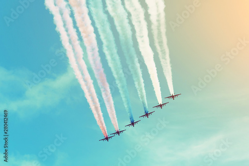 Group of aircraft flies in a row leaving a smoky trail in the sky.