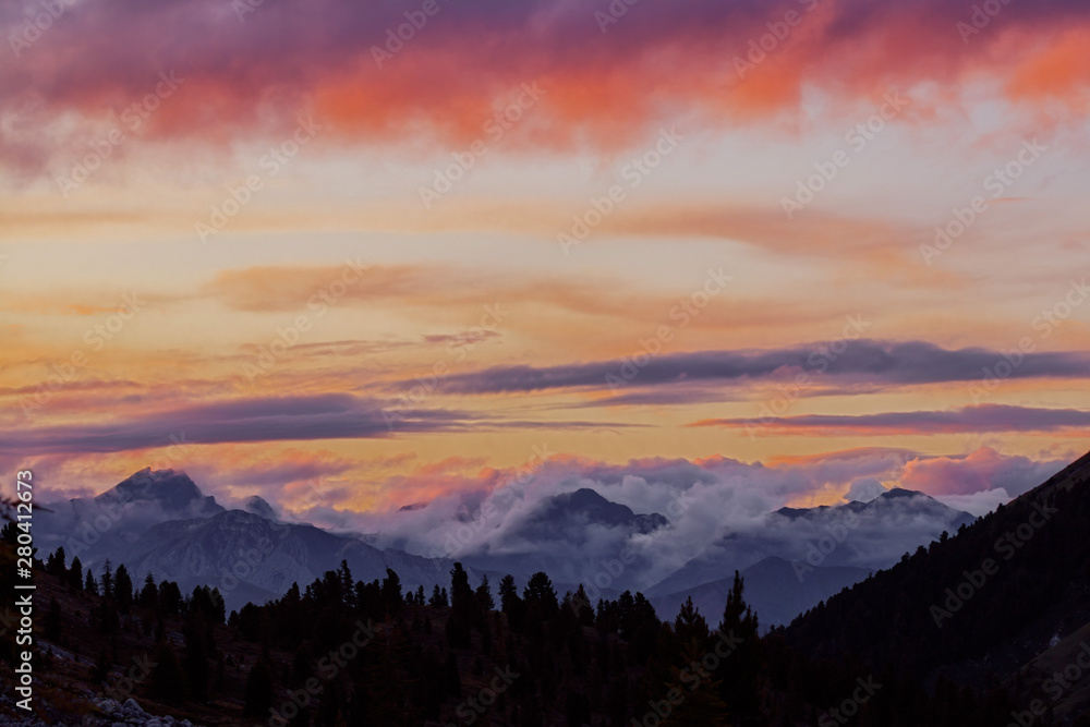 Panorama silhouette forest and mountain tops in red orange blue clouds gradient sunset