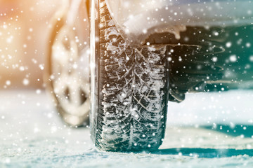 Close-up of car wheels rubber tires in deep winter snow. Transportation and safety concept.