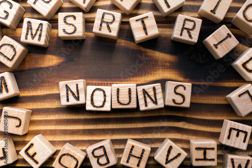 nouns composed of wooden cubes with letters, Part of speech concept scattered around the cubes random letters, top view on wooden background photo