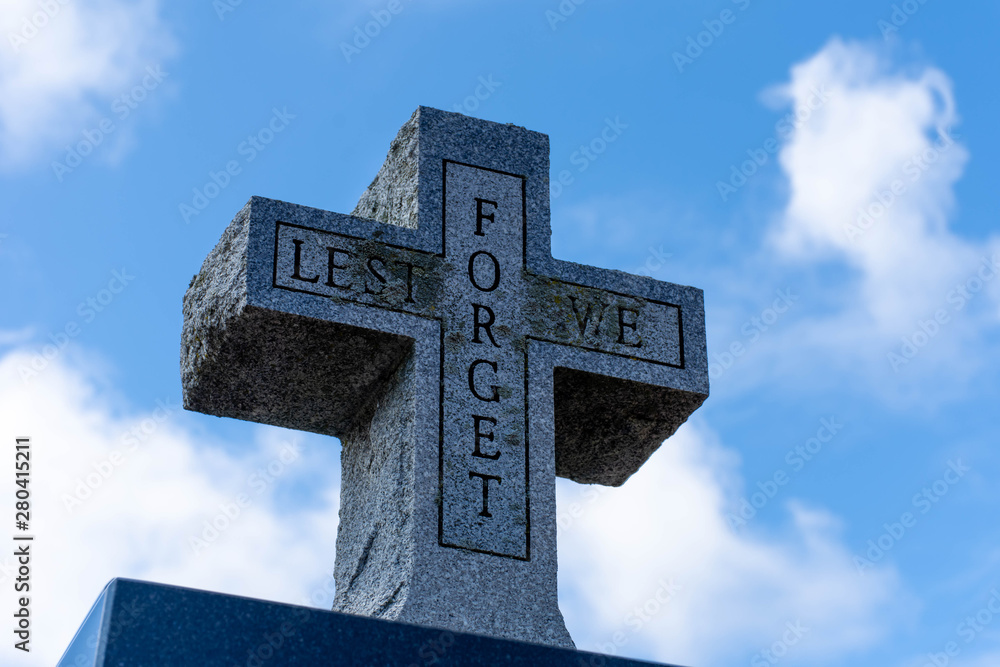 Lest we Forget stone cross memorial for world war two veterans on a blue sky cloudy background. Lest we Forget stone cross memorial for world war two veterans on a blue sky cloudy background.