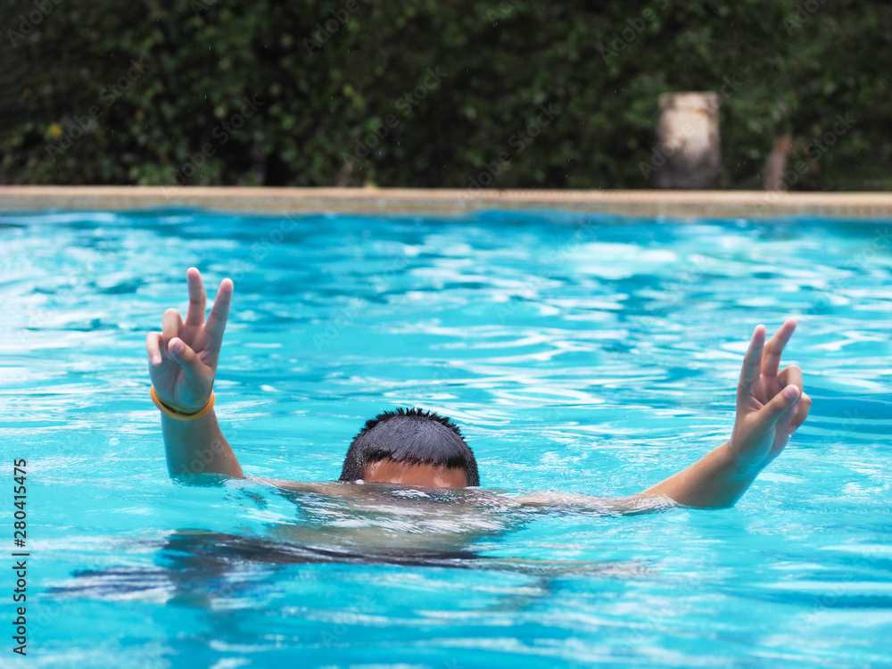 Active Boy diving and raising hands in the air at outdoor swimming pool Kids enjoy playing on summer weekend holidays at resort.