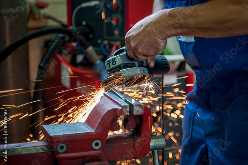 Handwerker schleift Werkstück aus Metall im Schraubstock mit dem Winkelschleifer, Nahaufnahme