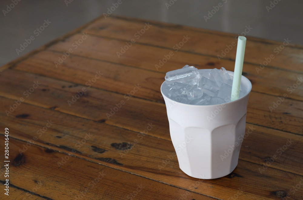 Glass of water, put ice on the wooden table Glass of water, put ice on the wooden table