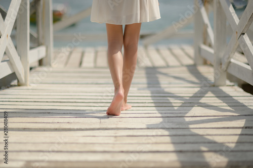 bare foot or legs of slim woman walks on wooden bridge pier to the seaside, feel freedom and comfortable walking alone close to beach nature