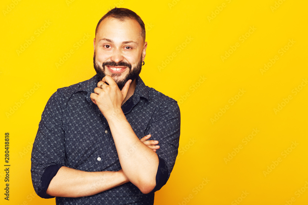 Fabulous at any age. Profile portrait of charismatic 35 years old man standing over yellow background with crossed hands. Short modern haircut. Hipster style. Copy-space. Studio shot Fabulous at any age. Profile portrait of charismatic 35 years old man standing over yellow background with crossed hands. Short modern haircut. Hipster style. Copy-space. Studio shot