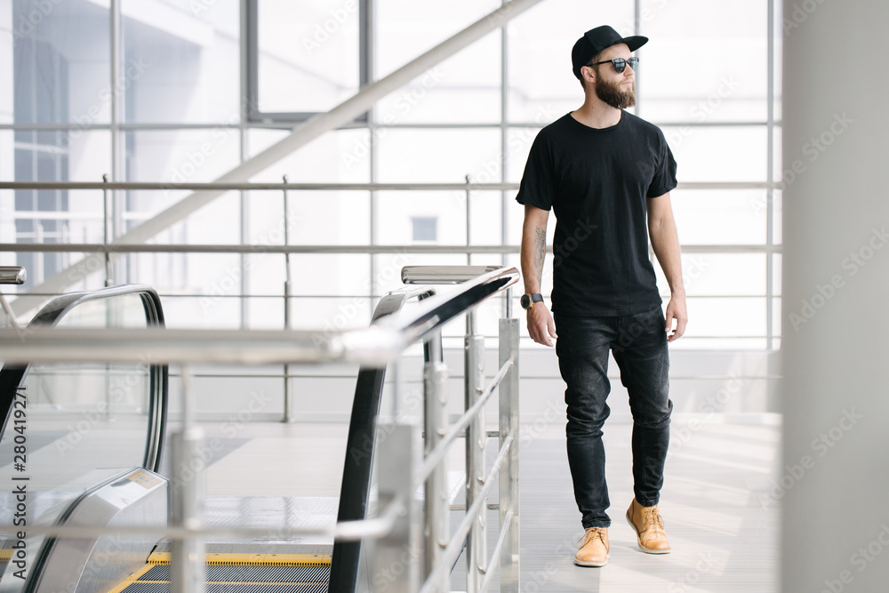 Hipster handsome male model with beard wearing black blank t-shirt with space for your logo or design in casual urban style Hipster handsome male model with beard wearing black blank t-shirt with space for your logo or design in casual urban style