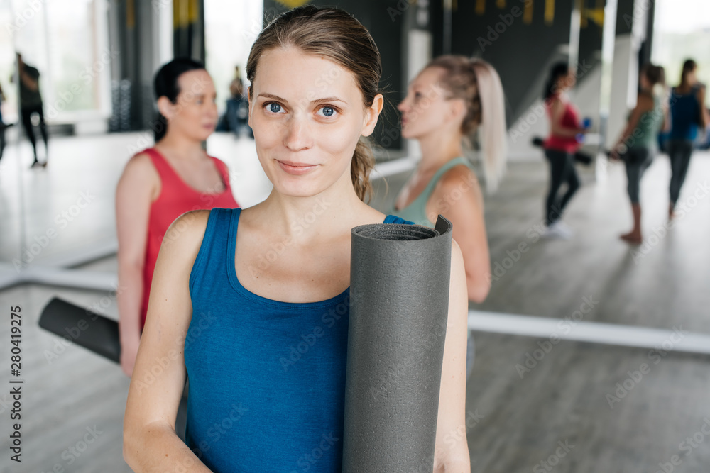 Obraz premium Pregnant women pose at the camera while talking and having folded yoga mats.