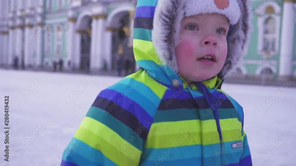 Portrait kid looking at camera with curious face, Active Child boy wearing woolen hat and scarf. Many people behind. Winter St. Petersburg Portrait kid looking at camera with curious face, Active Child boy wearing woolen hat and scarf. Many people behind. Winter St. Petersburg