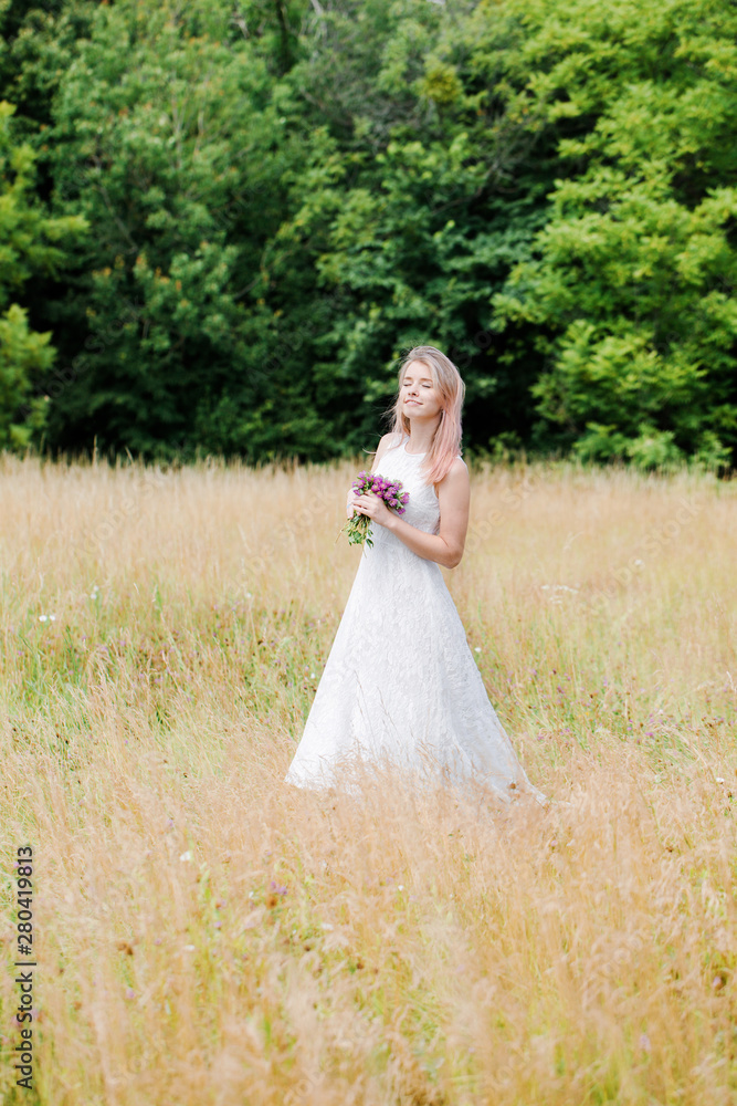 Young beautiful girl in a white vintage dress with a long train is holding a bouquet