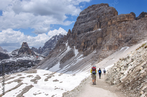 a group of tourists is walking along a wide trail in the Dolomites, Italy