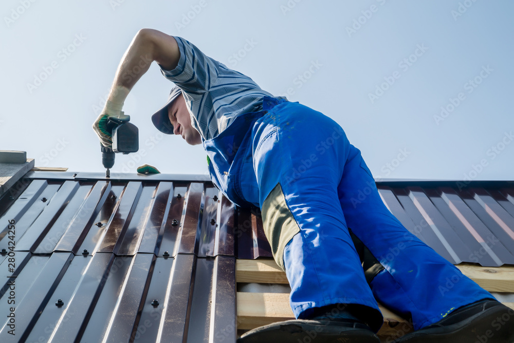 Fototapeta premium an employee performs roofing work, for fixing sheeting with self-tapping screws