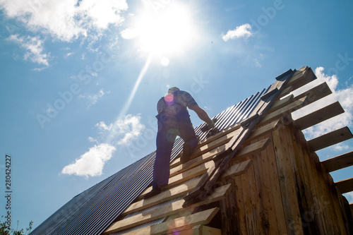 an employee performs roofing work, for fixing sheeting with self-tapping screws © vitec40