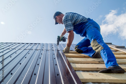 an employee performs roofing work, for fixing sheeting with self-tapping screws