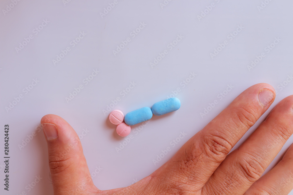 Hands of a man next to pills that symbolize a penis with an erection. Metaphor of male virility. Medicine related to male impotence. Hands of a man next to pills that symbolize a penis with an erection. Metaphor of male virility. Medicine related to male impotence.