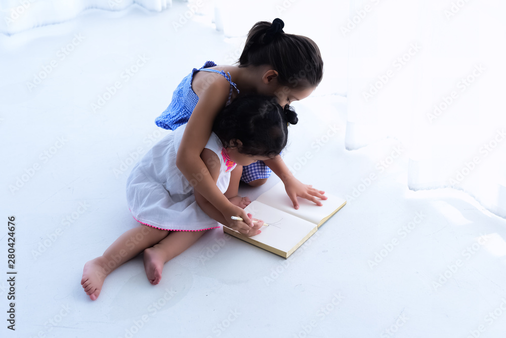 The elder sister teaching younger drawing,little girl  doing activity together,at home,blurry light around