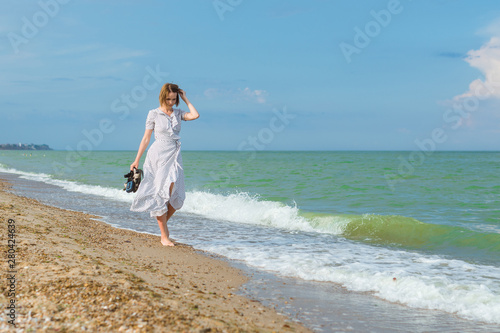 A woman in a dress walks along the seashore. Freedom, vacation concept.