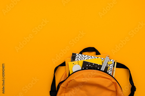 Back to school concept. Backpack with school supplies on yellow background. Top view. Copy space. Flat lay photo