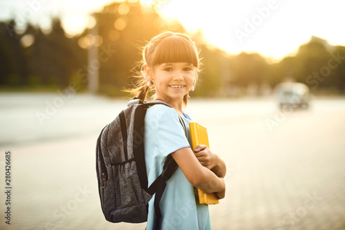 Happy little student girl with a backpack on her way to school.