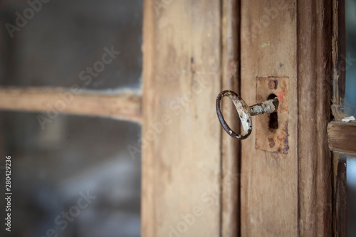 Una llave antigua en una cerradura de una puerta de madera con cristales