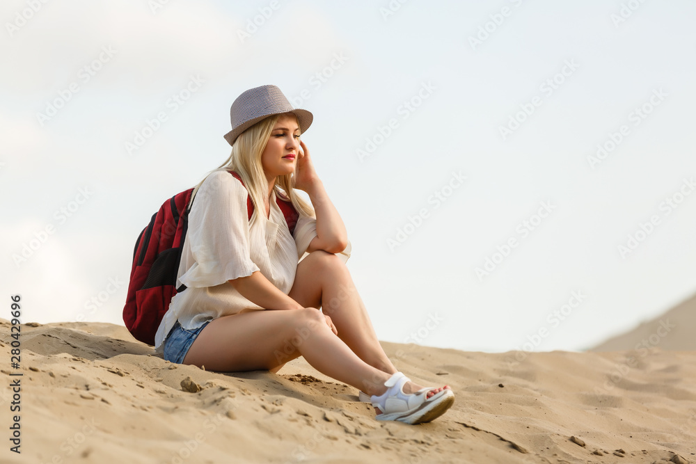girl with hat and backpack traveling, resting, desert