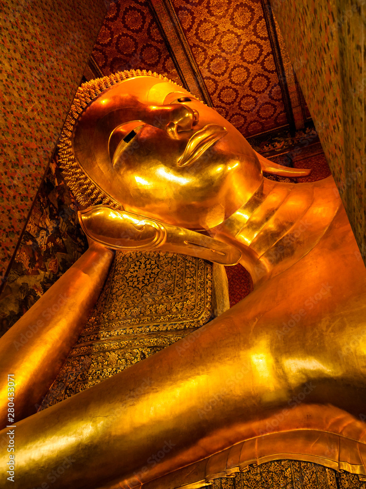 Beautiful face of Reclining Buddha, and thai art architecture in Wat Phra Chetupon Vimolmangklararm (Wat Pho) temple They are public domain or treasure of Buddhism in Thailand.